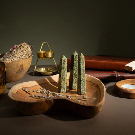 Three polished green epidote six face obelisk points stand upright on a rustic wooden tray