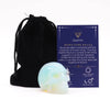 A polished gemstone skull made of translucent opalite with swirling light blue and pale yellow hues