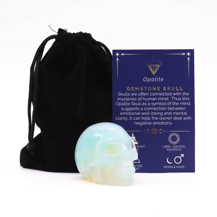 A polished gemstone skull made of translucent opalite with swirling light blue and pale yellow hues