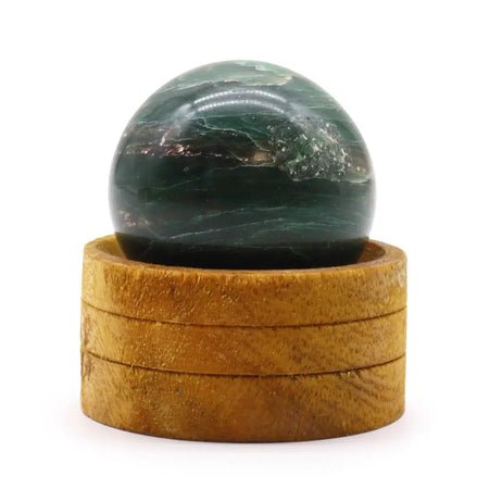 A polished green aventurine gemstone sphere on a stacked wooden base featuring indian jade material