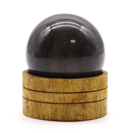 A polished black obsidian sphere with golden flecks on a wooden base labeled as ocean agate gemstone sphere 50mm
