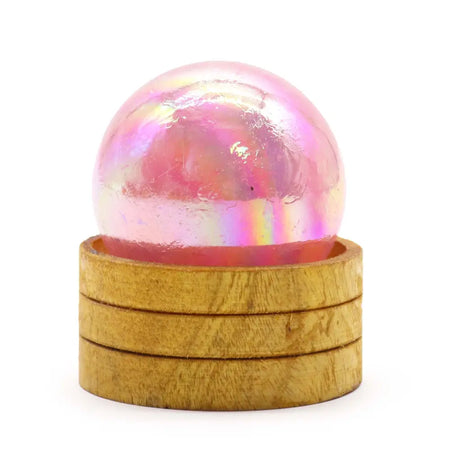 A translucent pink rose quartz titanium aura crystal sphere on a stacked wooden base 50mm gemstone sphere