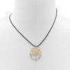 A carnelian gemstone tree of life pendant with yellow crystals in a silver frame hanging from a black cord