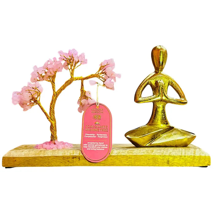 Golden mango wood meditation figure in namaste pose seated beside genuine rose quartz tree sculpture