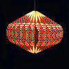 A vibrant red and black geometric origami paper pendant lamp with a warm yellow glow for indoor lighting