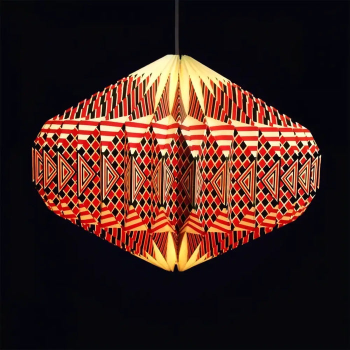 A vibrant red and black geometric origami paper pendant lamp with a warm yellow glow for indoor lighting