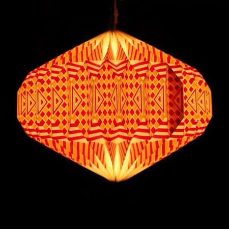 A glowing orange and red hexagonal paper lantern with a geometric origami pattern in a warm light shade