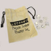Beige drawstring bag with black embroidery holding a clear quartz seven piece geometric crystal set
