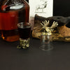 A clear glass shot glass with an antique bronze moose head stopper and base from mystical creatures set