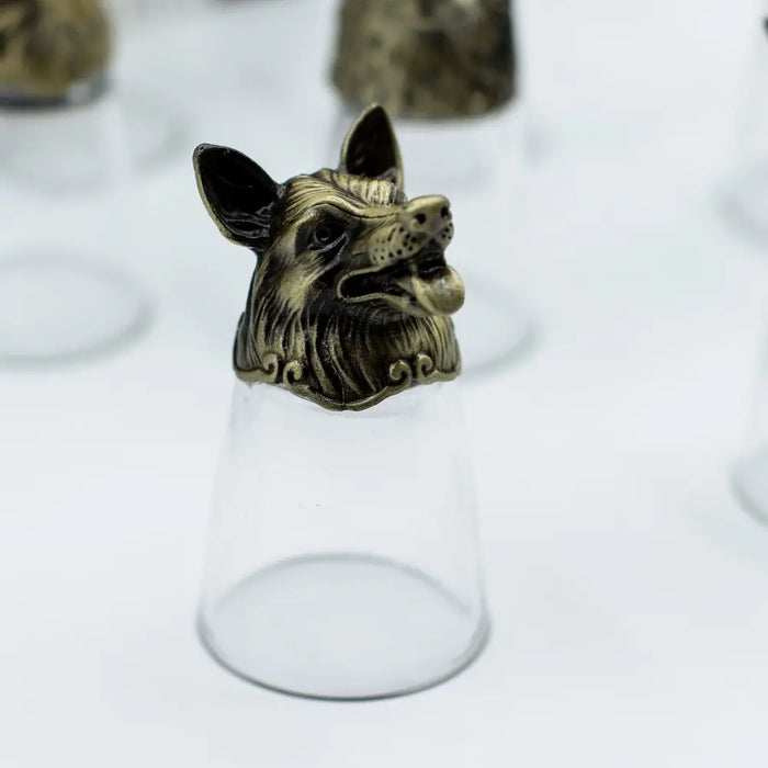 Antique bronze fox head ring with detailed fur rests on a clear glass from mystical creatures shot glasses set