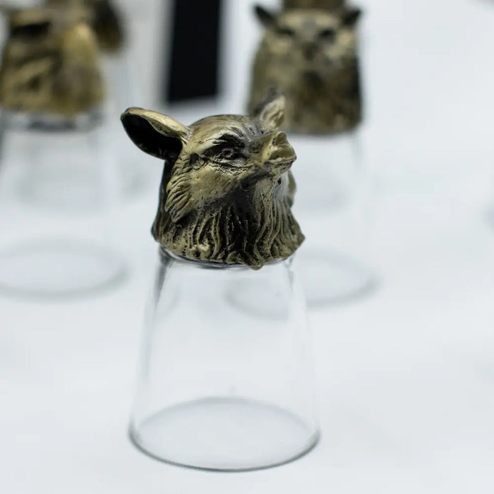 A clear glass shot glass topped with an antique bronze owl stopper from mystical creatures shot glasses set