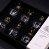 Six clear glass bottles with antique bronze crowns in a black gift box featuring mystical creatures glass features