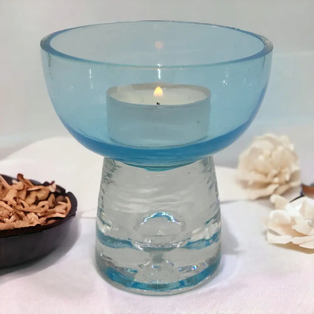 A glass candle holder with a pale blue bowl and clear textured base for tealight candles