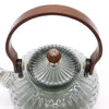 A clear glass infuser teapot with a charcoal ribbed body and wooden handle for brewing tea at home
