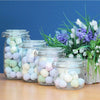 Clear glass kilner storage jars with silver metal clasp lids filled with pastel bath bombs in four sizes