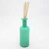 A sleek translucent teal glass reed diffuser bottle with a slender neck and rounded base for home fragrance