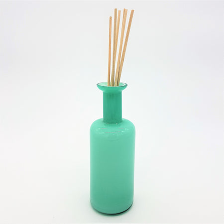 A sleek translucent teal glass reed diffuser bottle with a slender neck and rounded base for home fragrance