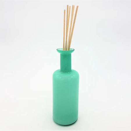 A sleek translucent teal glass reed diffuser bottle with a slender neck and rounded base for home fragrance