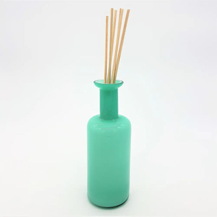 A sleek translucent teal glass reed diffuser bottle with a slender neck and rounded base for home fragrance