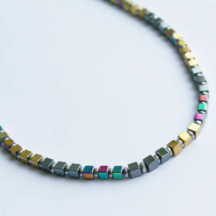 A gold finish grey and rainbow hematite block beaded necklace with metallic square magnetic beads and iridescent accents