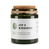 A dark green glass woodwick soy candle with cork lid and twine wrap labeled ash and woodsmoke by greenman naturals