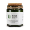 A dark green glass cedar citrus woodwick soy candle jar by greenman naturals with cork lid and twine wrap