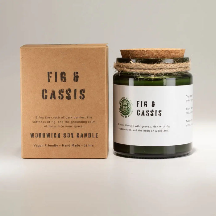 Dark green glass jar soy candle with cork stopper and twine labeled fig and cassis next to brown box packaging