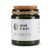 A dark green glass jar woodwick soy candle by greenman woodwick labeled moss and mist with cork lid and twine wrap