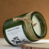 A greenman woodwick soy candle in a green glass jar with white wax, wooden wick, and twine around the neck