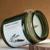 A dark green glass jar woodwick soy candle with wild lavender scent and botanical label wrapped in twine