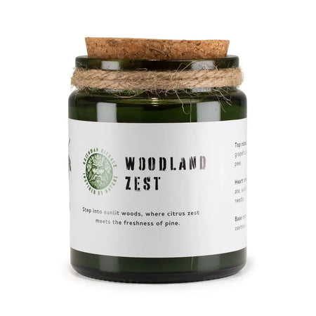 A green glass greenman woodwick soy candle jar with cork lid and twine labeled woodland zest by greenman oils