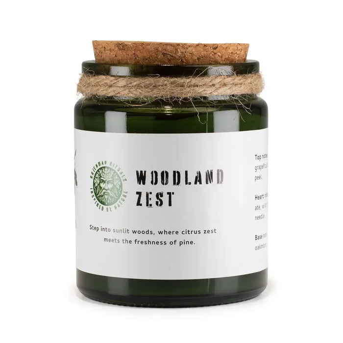 A green glass greenman woodwick soy candle jar with cork lid and twine labeled woodland zest by greenman oils