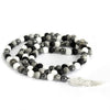 A coiled grey agate necklace with black white and gray stone beads and a silver angel wing charm