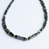 A sleek black and gold finish hematite block beaded necklace with magnetic cube and metallic accents