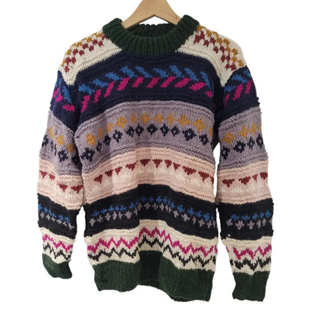 A gringo fairtrade wool jumper with a colorful geometric pattern and ribbed cuffs in navy blue cream pink and mustard yellow