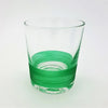 A clear glass votive with a vibrant green ribbed band around the lower half used as a tealight holder