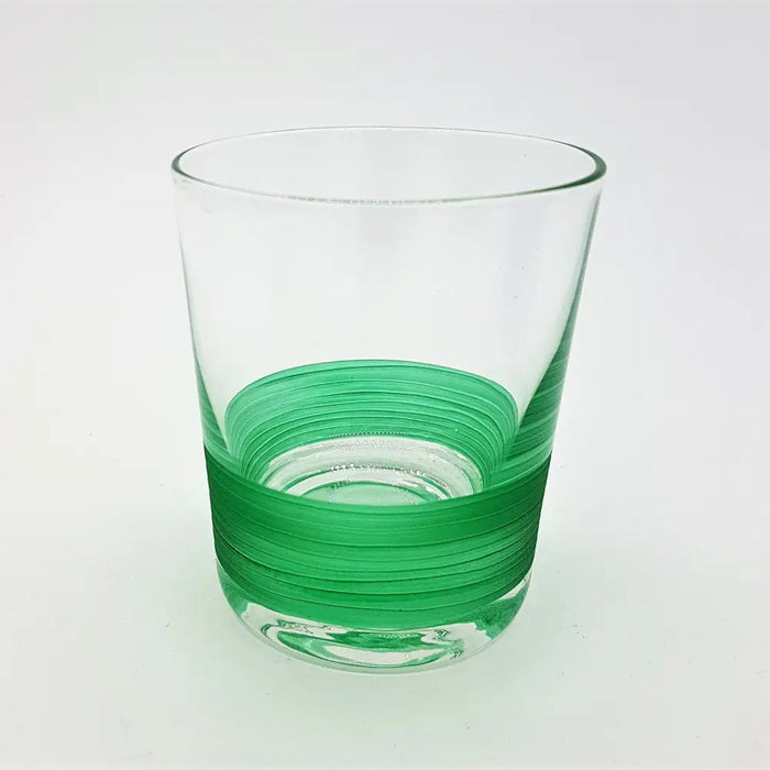 A clear glass votive with a vibrant green ribbed band around the lower half used as a tealight holder
