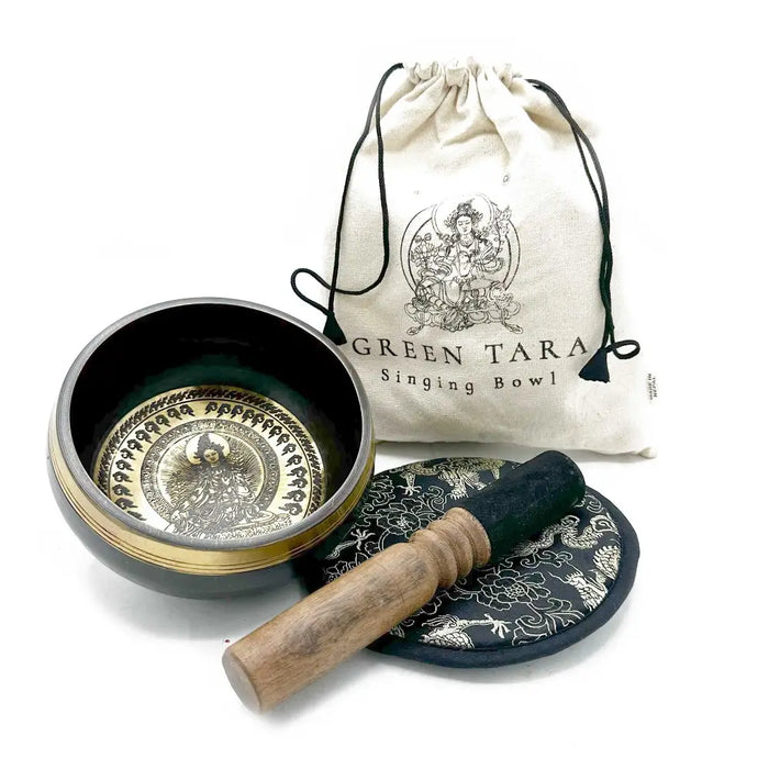 A dark green and gold engraved singing bowl with wooden mallet on an ornate black cushion green tara gift set