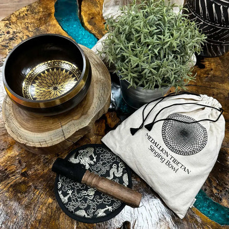 A polished bronze engraved singing bowl with golden geometric pattern resting on a wooden stand in a bowl gift set