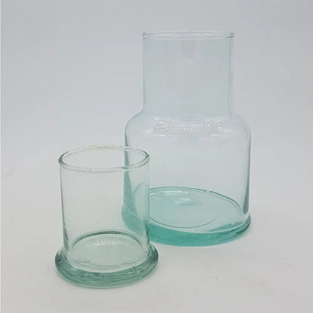 Clear glass hand-blown recycled glass jug with a short neck and rounded base next to a smaller matching glass