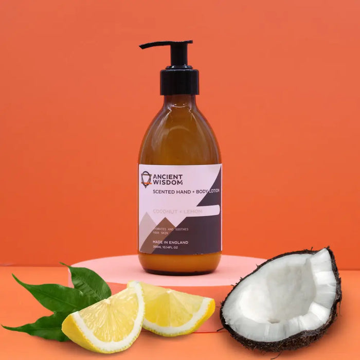 An amber glass bottle of ancient wisdom body lotion with coconut lemon scent and black pump on a pink pedestal