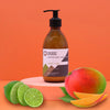A sleek amber glass bottle of ancient wisdom mango and lime body lotion with seed oil on a pink pedestal