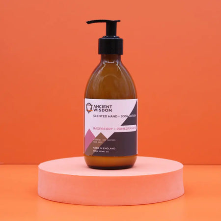 A sleek amber glass bottle of hand and body lotion with black pump in raspberry and pomegranate scent and seed oil