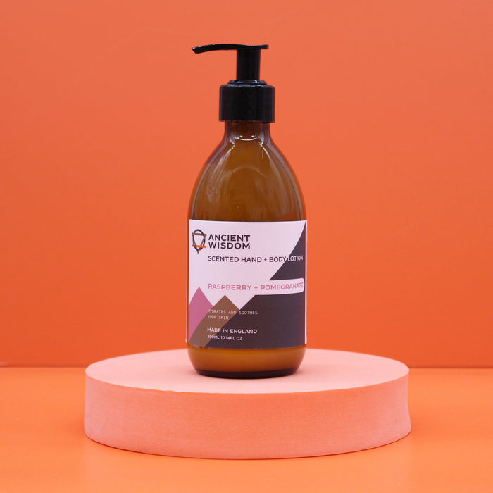 A sleek amber glass bottle of hand and body lotion with black pump in raspberry and pomegranate scent and seed oil