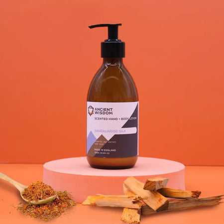 A sleek amber glass bottle of ancient wisdom hand and body lotion in sandalwood silk with black pump and seed oil