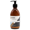 A sleek amber glass bottle of ancient wisdom hand and body lotion sandalwood silk with black pump dispenser and seed oil