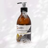 An amber glass bottle of ancient wisdom body wash with black pump and ginger plus orange label for hand and body use