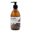 A sleek amber glass bottle with black pump labeled ancient wisdom sandalwood silk body wash 300ml