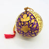 Hand-painted papier maché bauble in purple and gold with cream leaves and a red tassel decoration