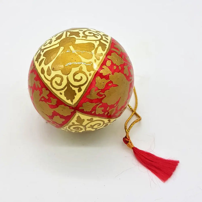 A hand-painted papier maché bauble in glossy red and gold with cream leaves and a matching tassel
